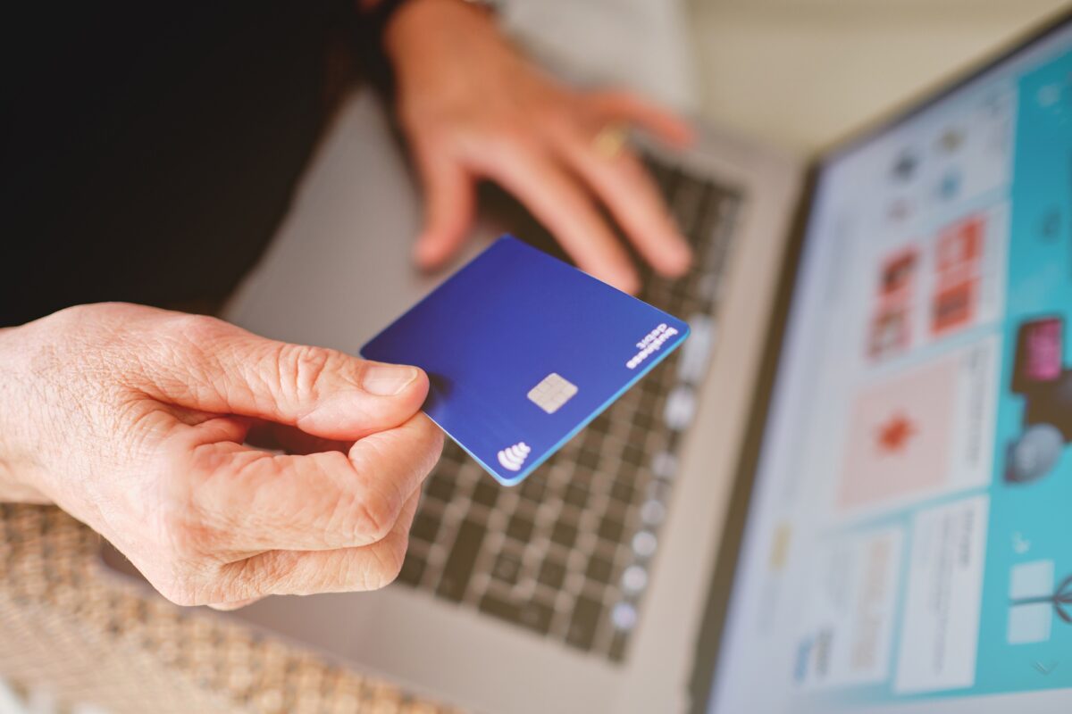 Femme adulte tenant une carte avec sa main devant l'ordinateur sur le point de régler un achat